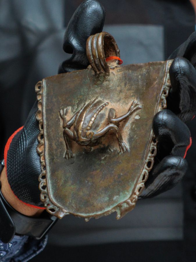 Ausgepackt: Anhänger mit der Darstellung eines Frosches. Wappenförmige Anhänger waren Teil der zeremoniellen Insignien von Mitgliedern der Palastgesellschaften. Sie wurden an einem Gürtel oder als Brustanhänger getragen.